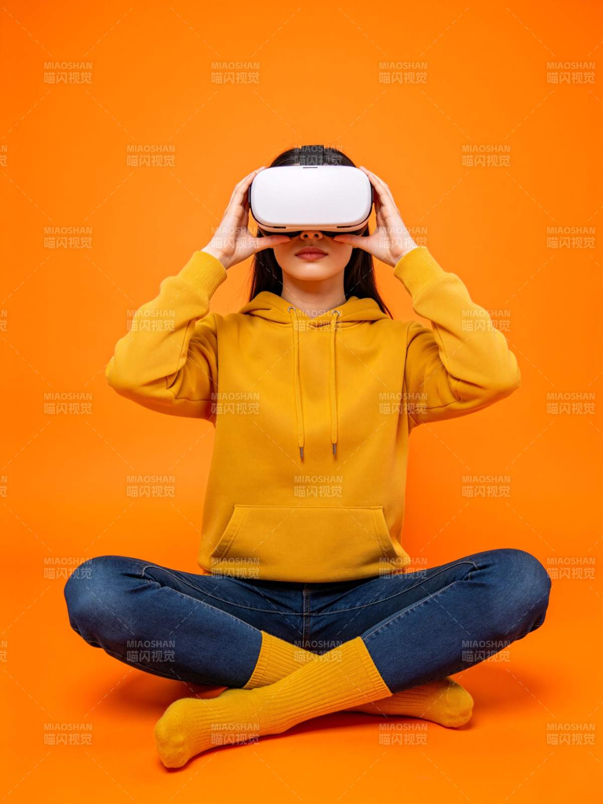 女子盘坐佩戴白色VR头显体验虚拟现实图片