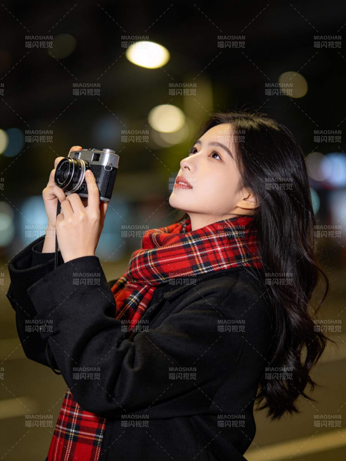 黑衣女子手持胶片相机夜拍街景图片