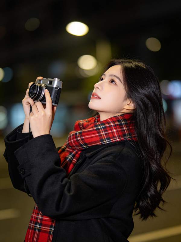 黑衣女子手持胶片相机夜拍街景图片