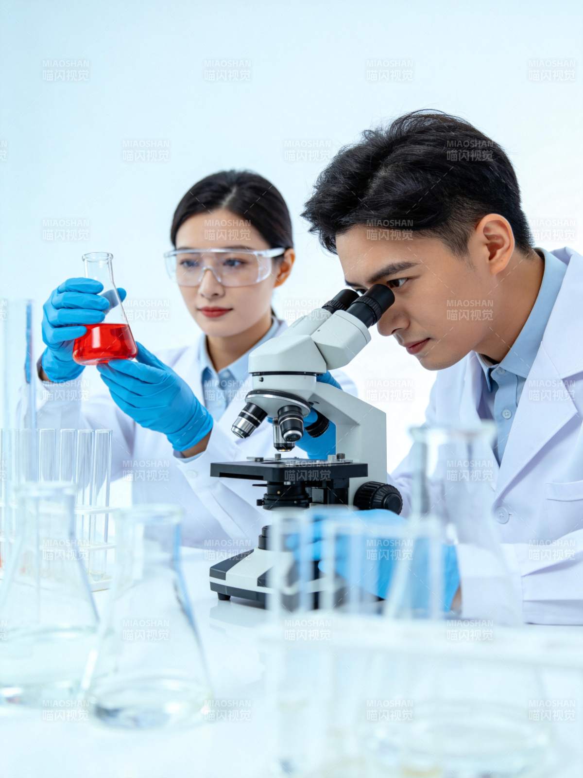 科研人员在实验室使用显微镜观察红色液体样图片