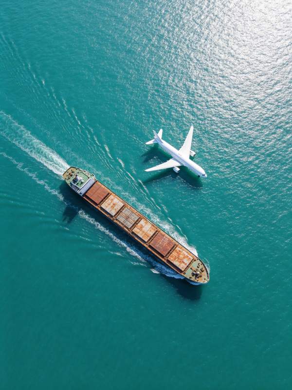 货轮与客机在碧蓝海面并行航行图片