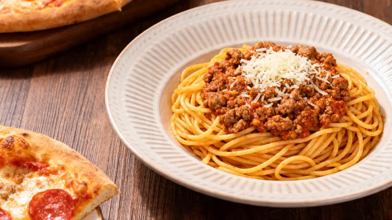 意面配肉酱 旁有披萨片图片