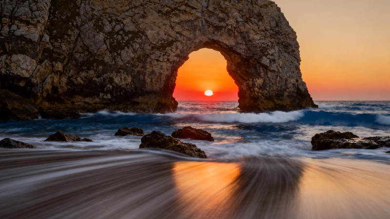 日落穿岩 海浪抚沙图片