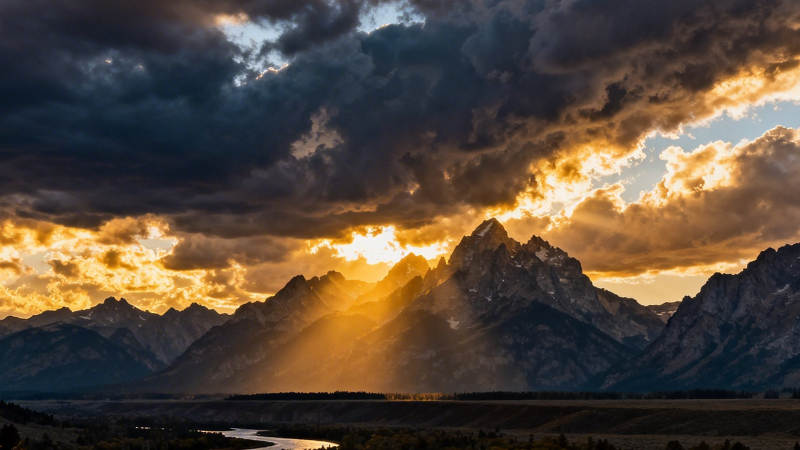 夕阳穿云照雪山图片