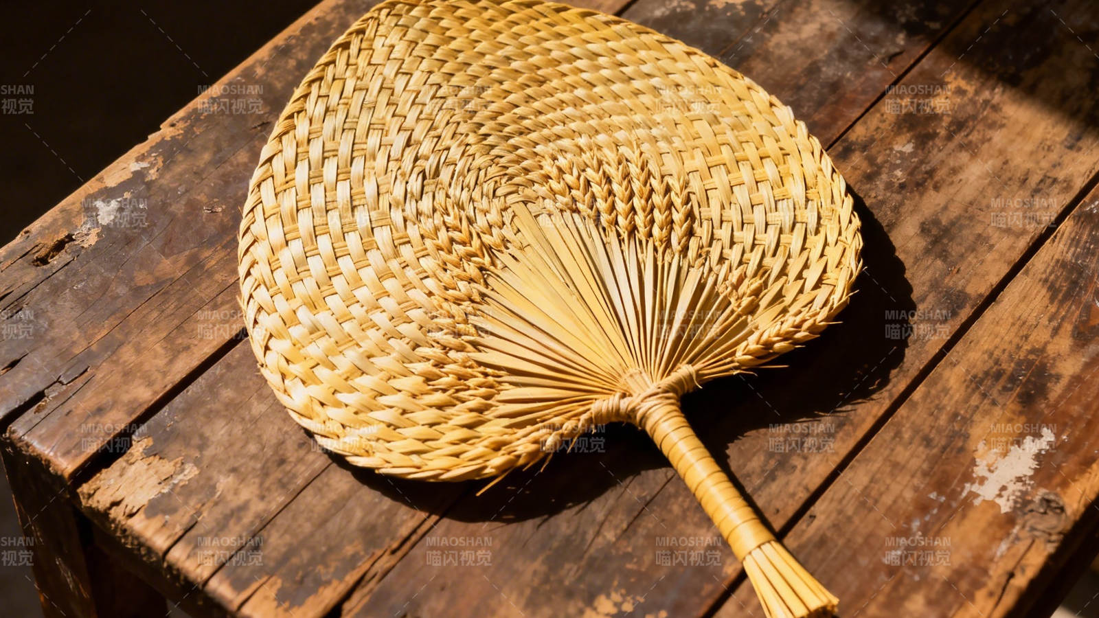 竹编扇静置木桌 光影斑驳图片