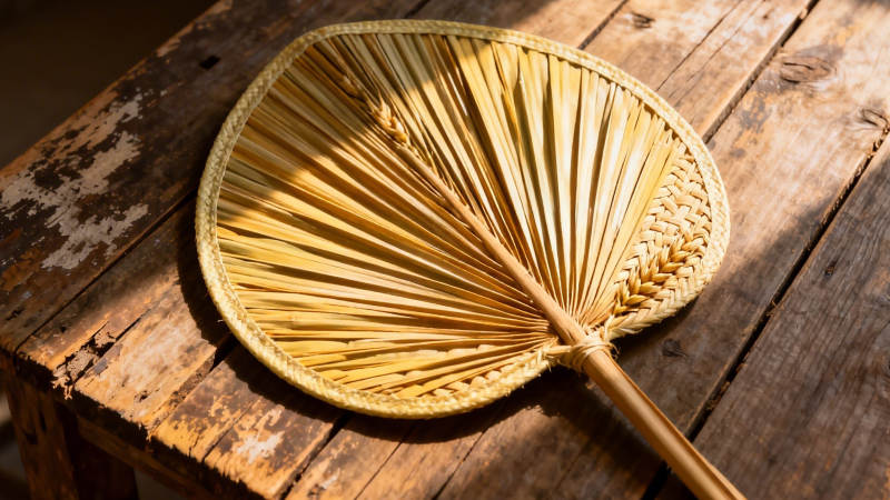 竹扇静置木桌 光影斑驳图片