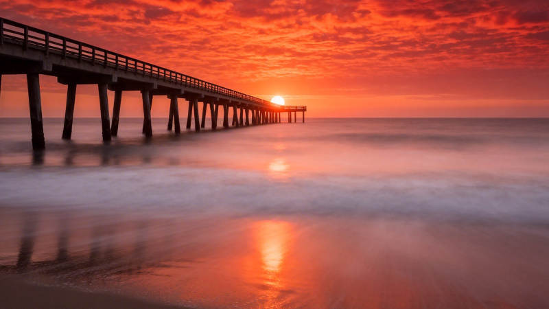 夕阳红染海天栈桥影图片