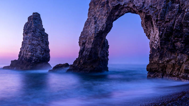 海蚀拱门与孤岩暮色图片