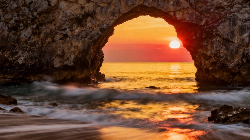 石拱门框住落日海景图片