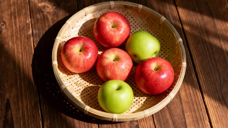 竹篮红绿苹果 阳光木纹桌图片
