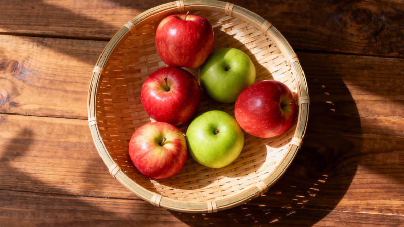 竹篮红绿苹果 阳光木纹桌图片
