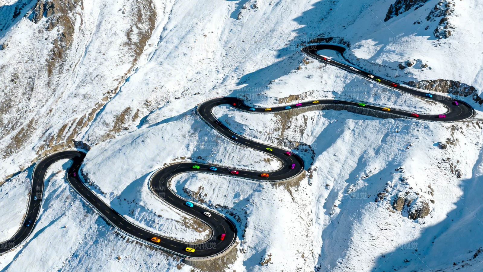 雪山蜿蜒公路彩车穿行图片