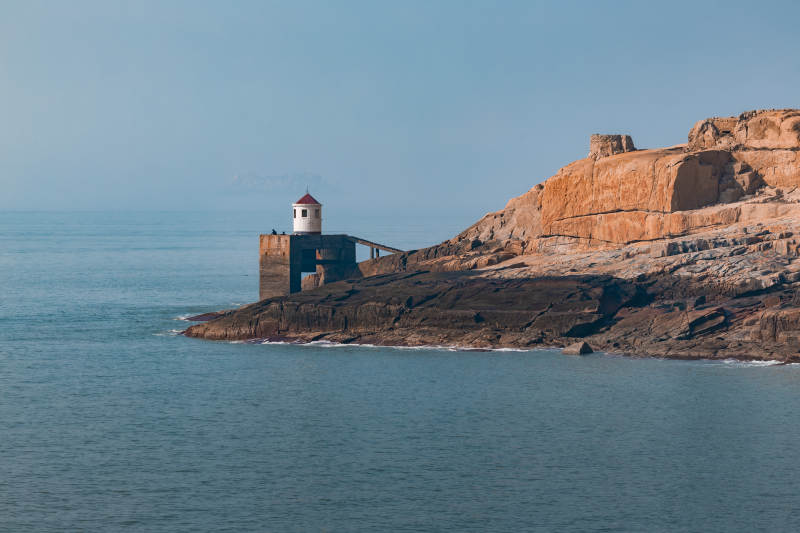 海边灯塔与红岩峭壁图片