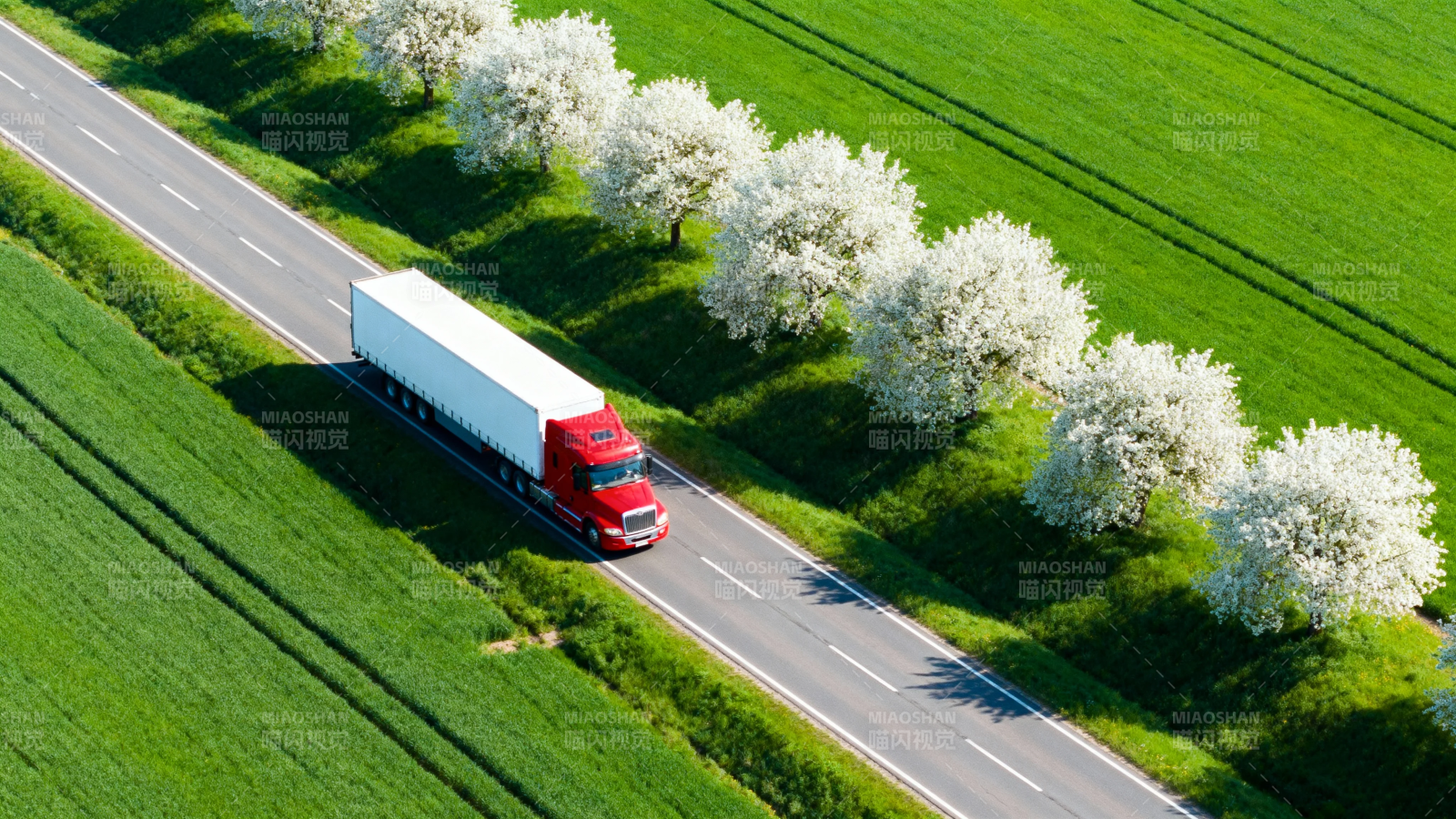 红卡车穿行花树绿野间图片