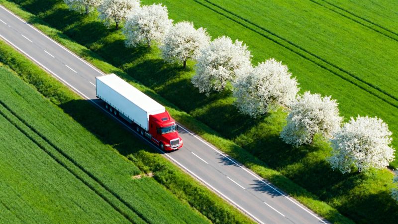 红卡车穿行花树绿野间图片