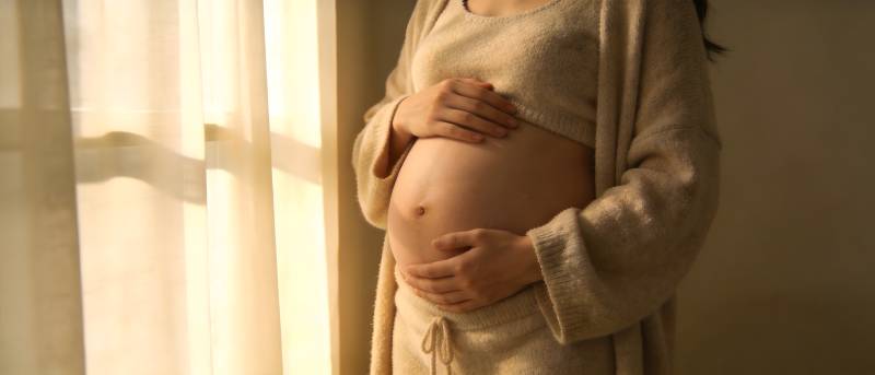 孕妈妈轻抚 belly 阳光温柔洒落图片