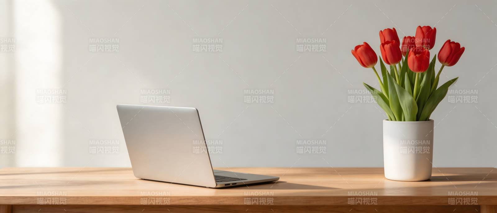 桌上一台笔记本和一束红花图片