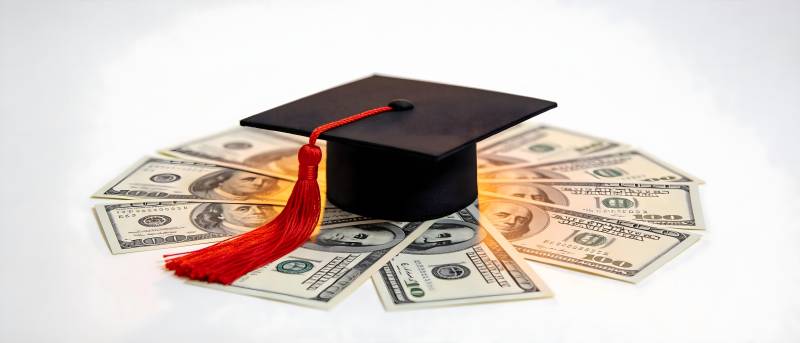 毕业帽与美元 教育投资回报图片