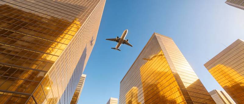 飞机掠过金色摩天楼群图片