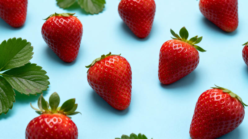 草莓散落蓝底 鲜红诱人图片