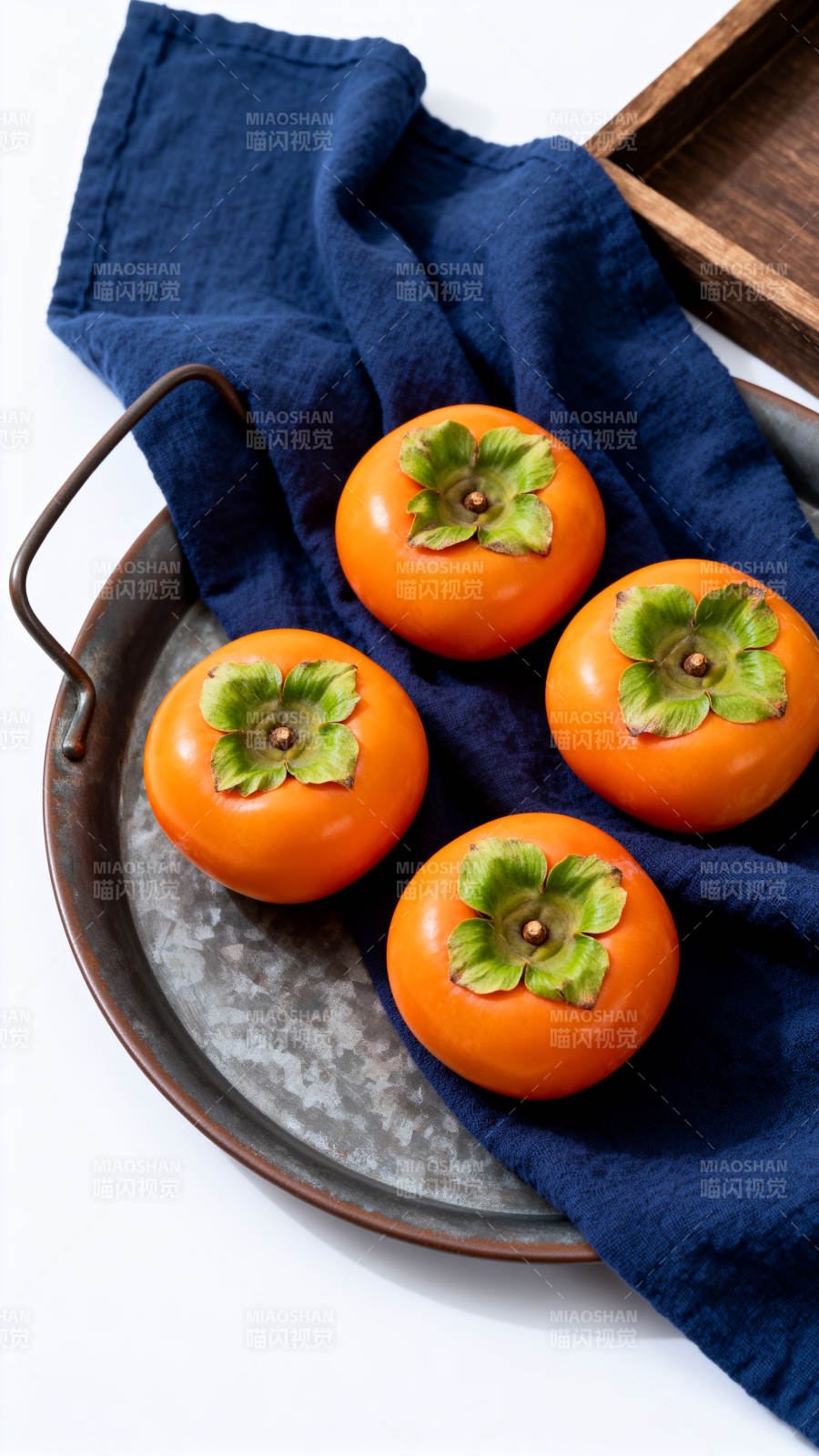 四颗柿子静置蓝布托盘上图片