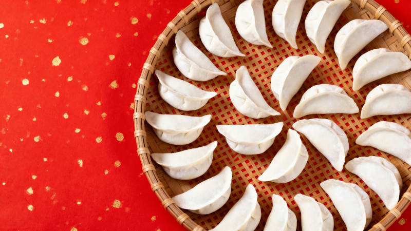 红底金点 饺子环列竹篮中图片