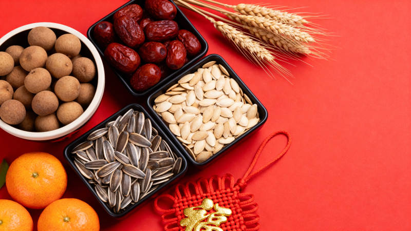 年货坚果红枣橘子麦穗红底图片