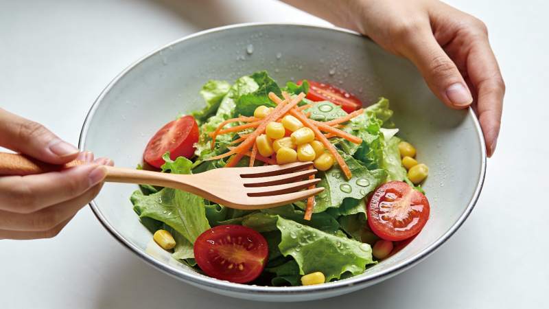 手握木叉享鲜蔬沙拉图片