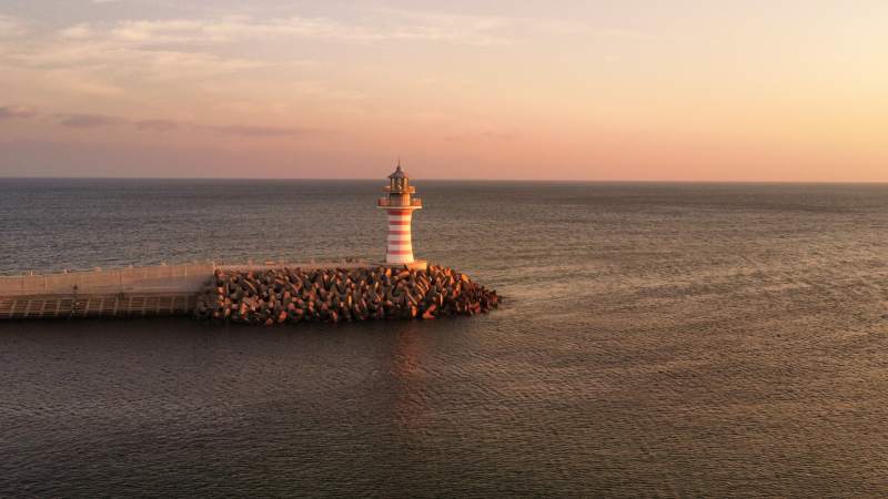 夕阳下的灯塔守望大海图片