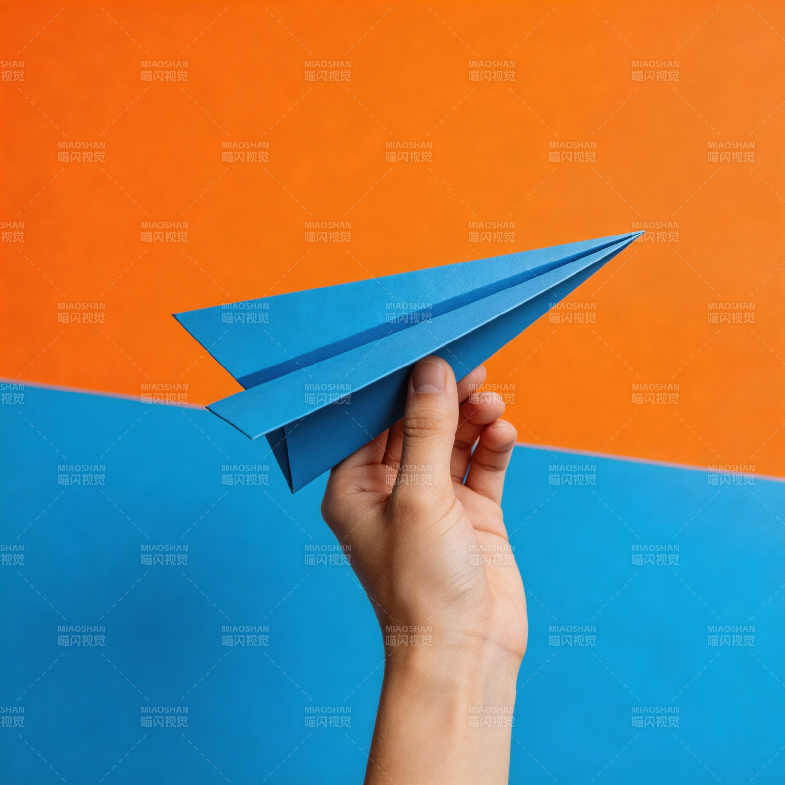 手握蓝纸飞机 橙蓝背景鲜明图片