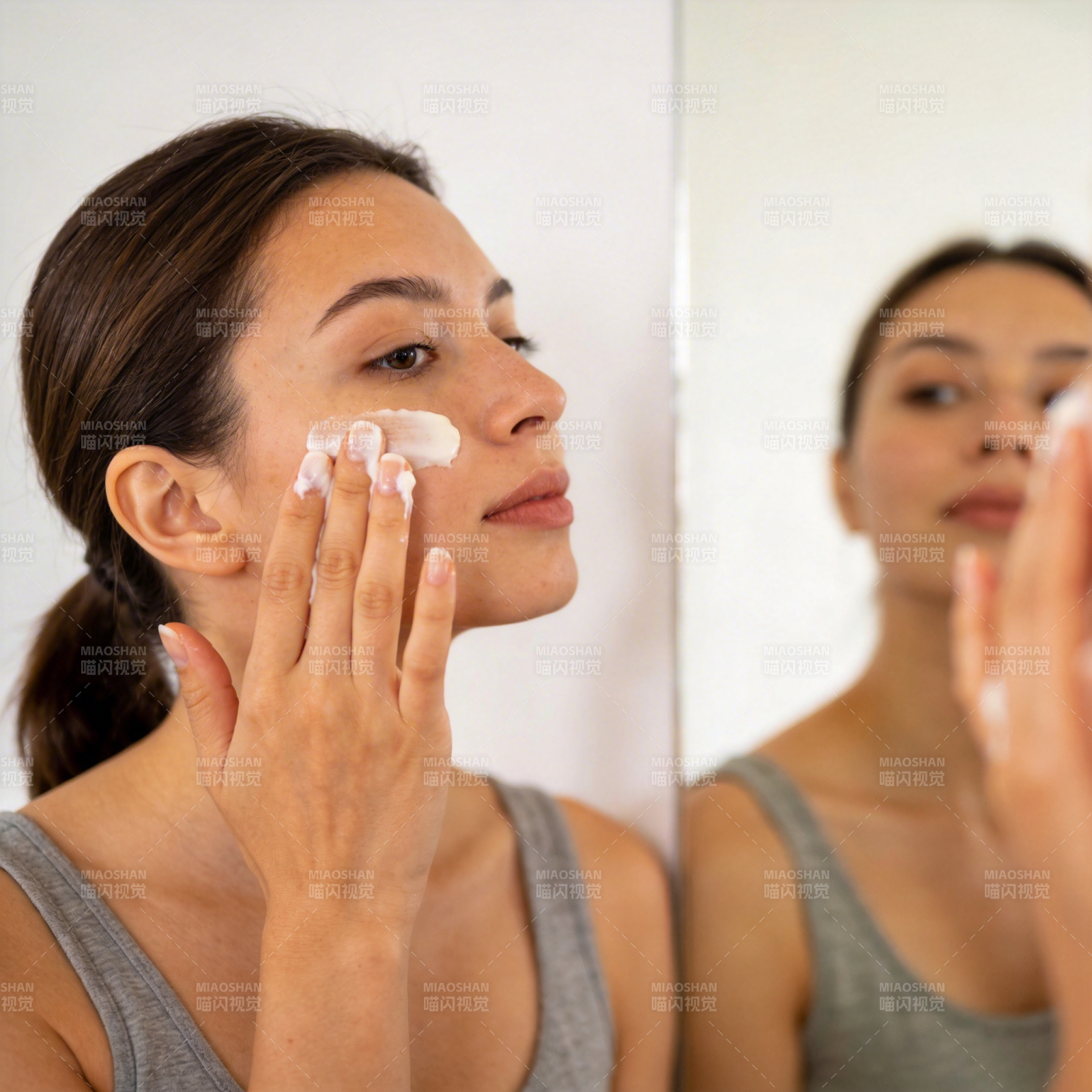 女子镜前涂抹面霜护肤图片