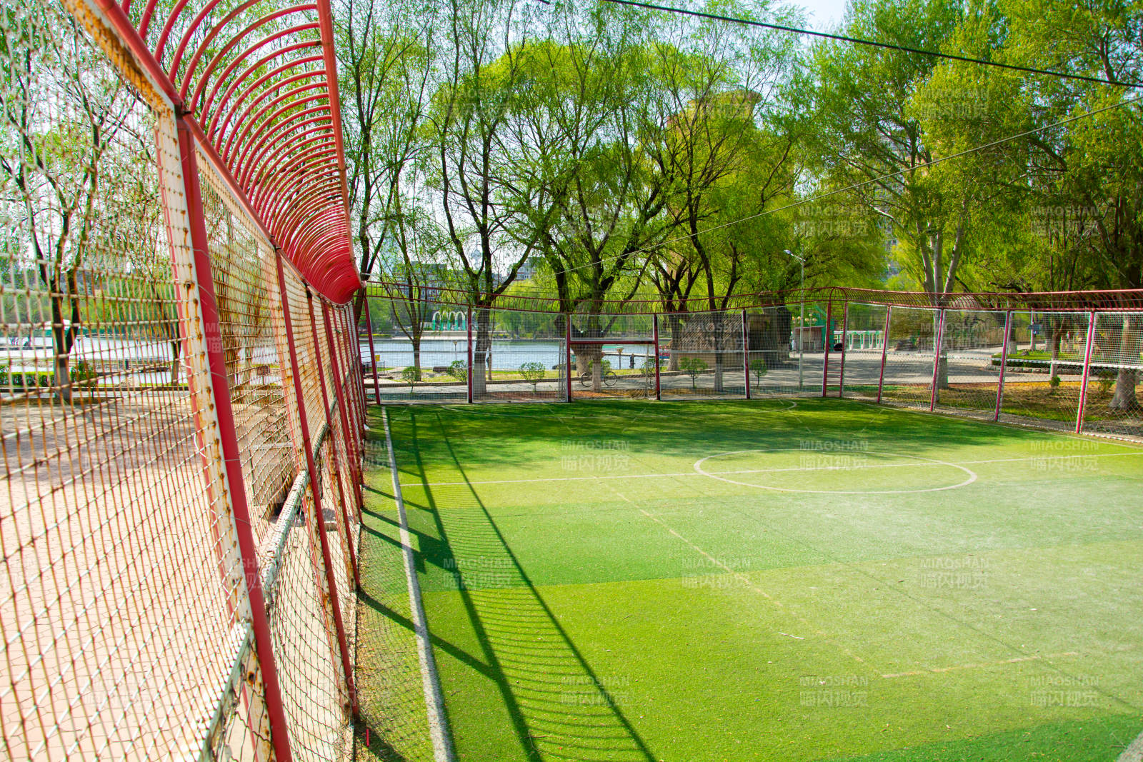 绿茵球场 红网环绕 树影婆娑图片