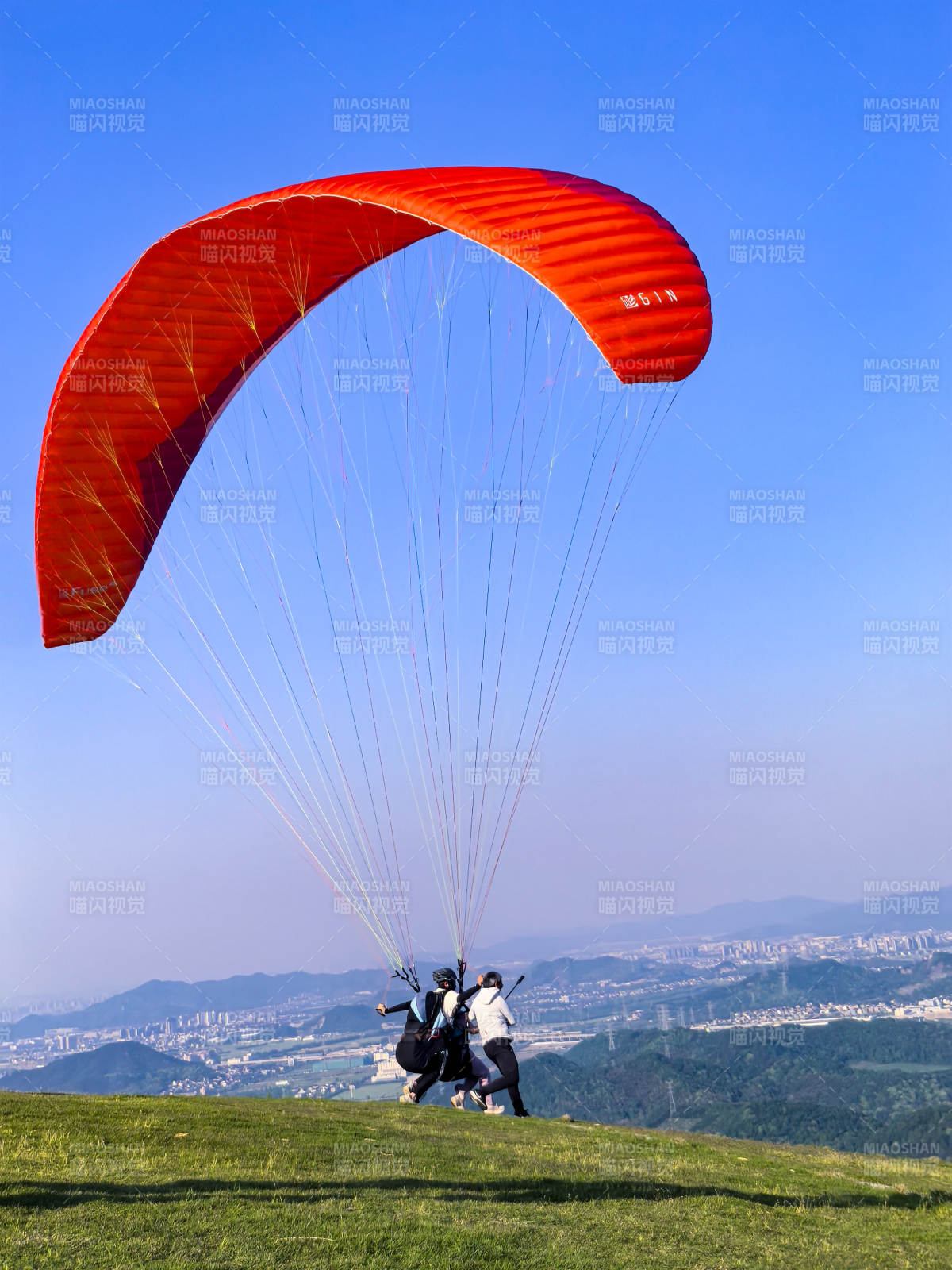 红伞滑翔 蓝天绿野间起飞图片