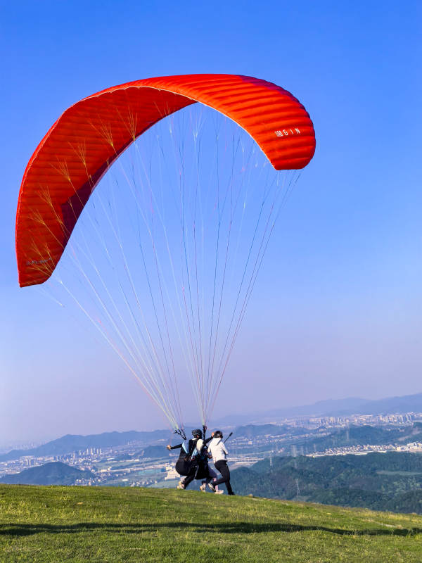 红伞滑翔 蓝天绿野间起飞图片