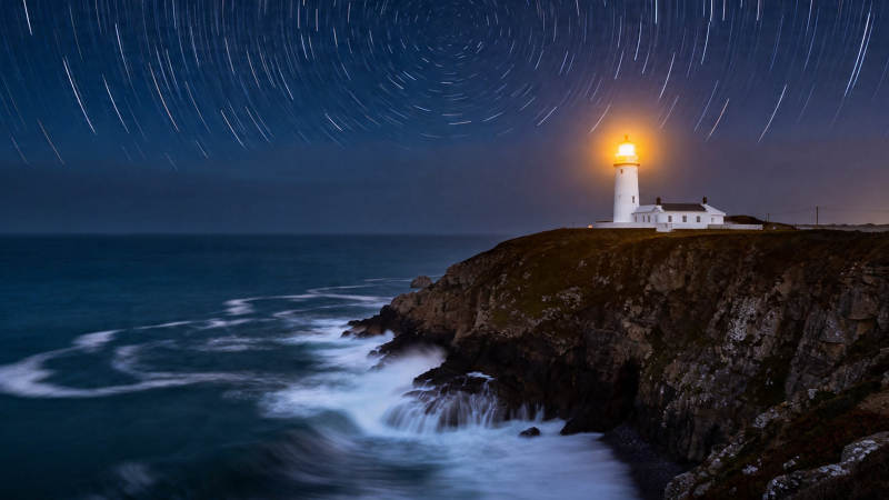 星轨下的灯塔守望夜海图片