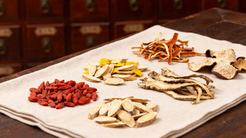 中药材陈列于布上 背景药柜图片