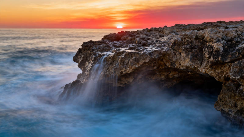 夕阳海浪拍岩洞图片