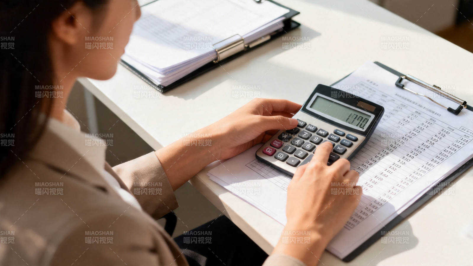 女子办公桌上用计算器算账图片