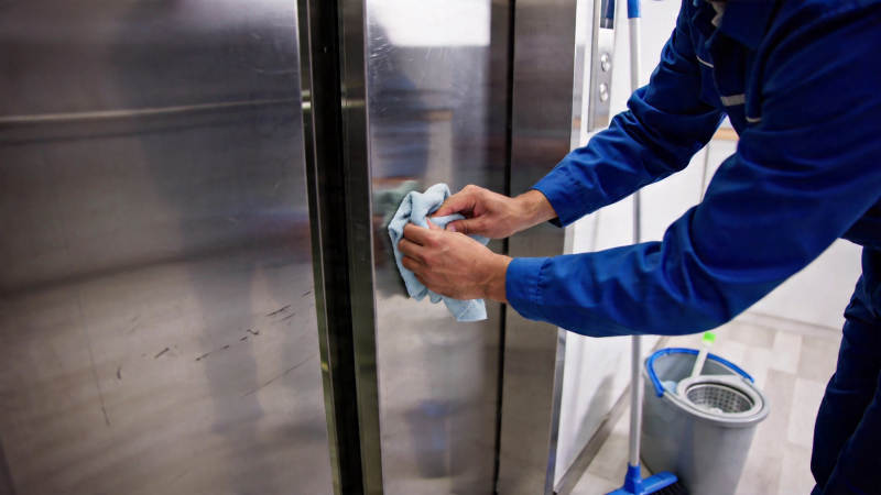 保洁员擦拭电梯门图片