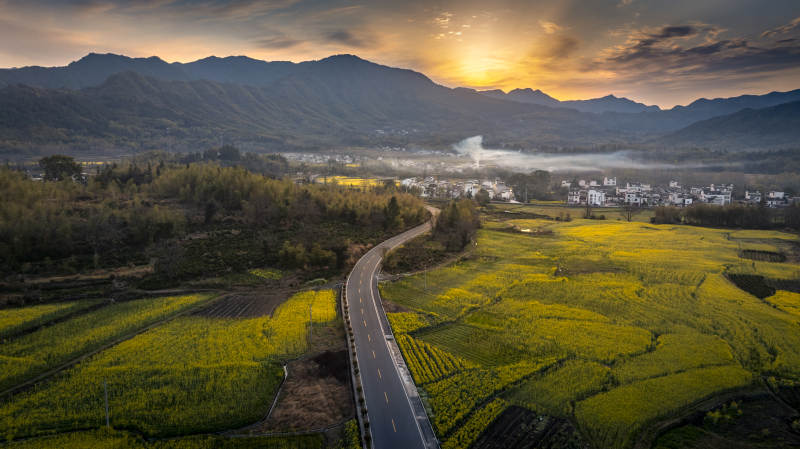 油菜花田伴山路 晨曦映远山图片