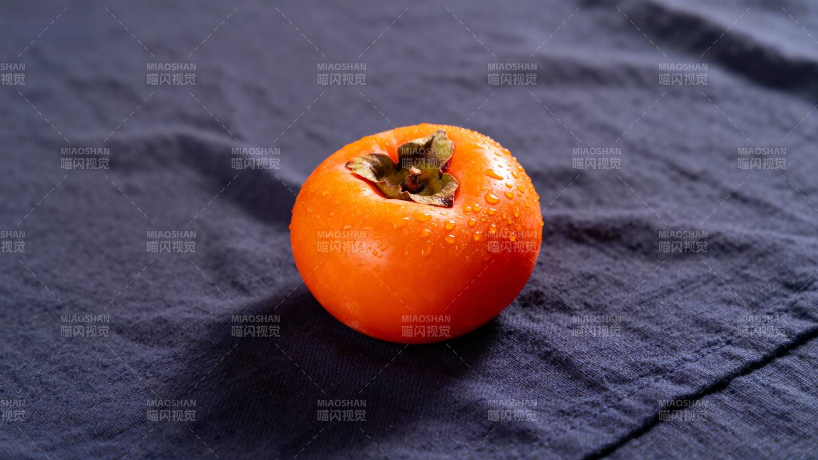 橙柿静卧深蓝布上图片