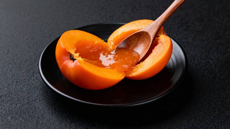 黑盘盛柿 木勺舀蜜图片
