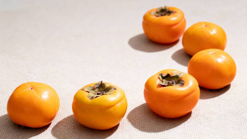 七颗柿子静置布面 橙黄诱人图片