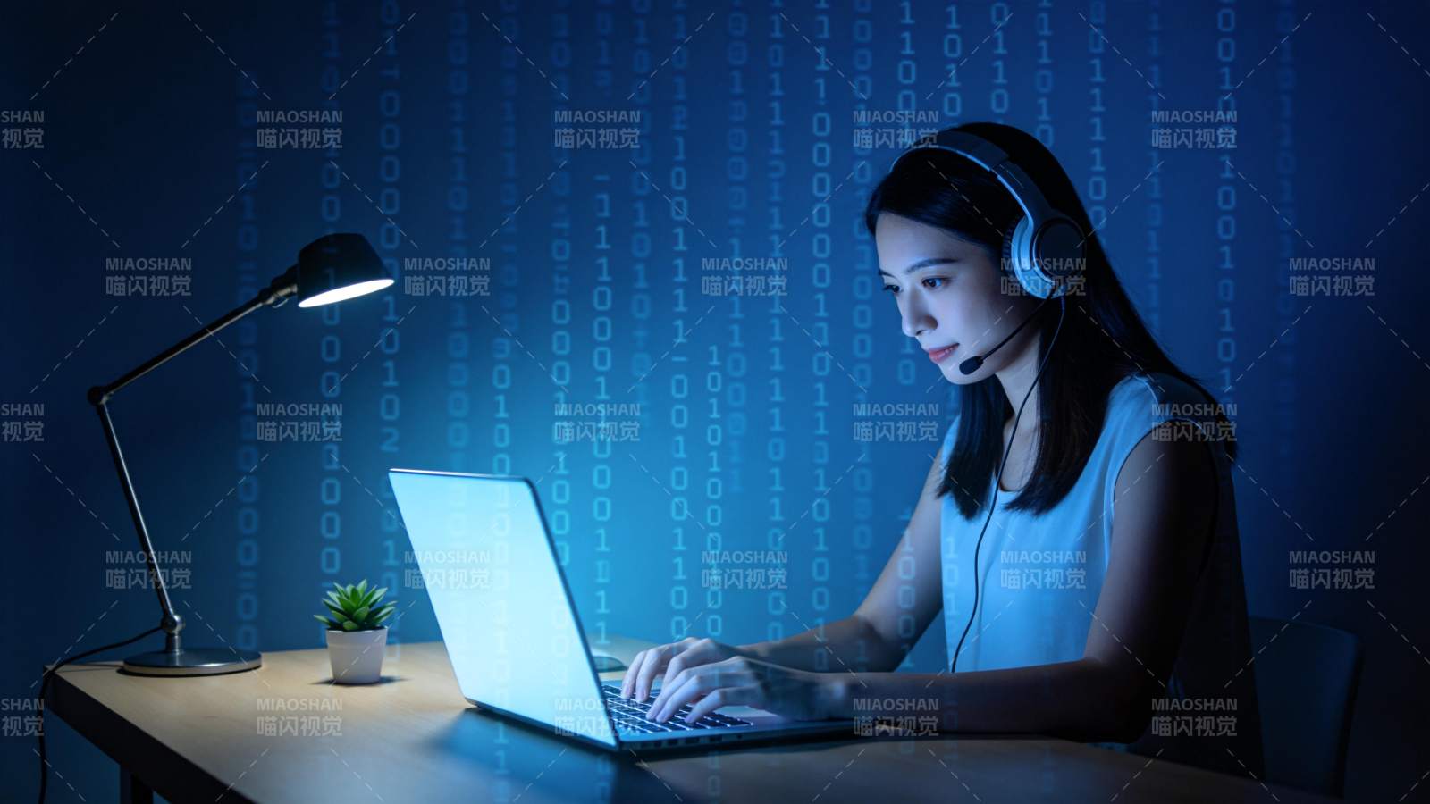 戴耳机女性在蓝光二进制背景前使用笔记本电图片