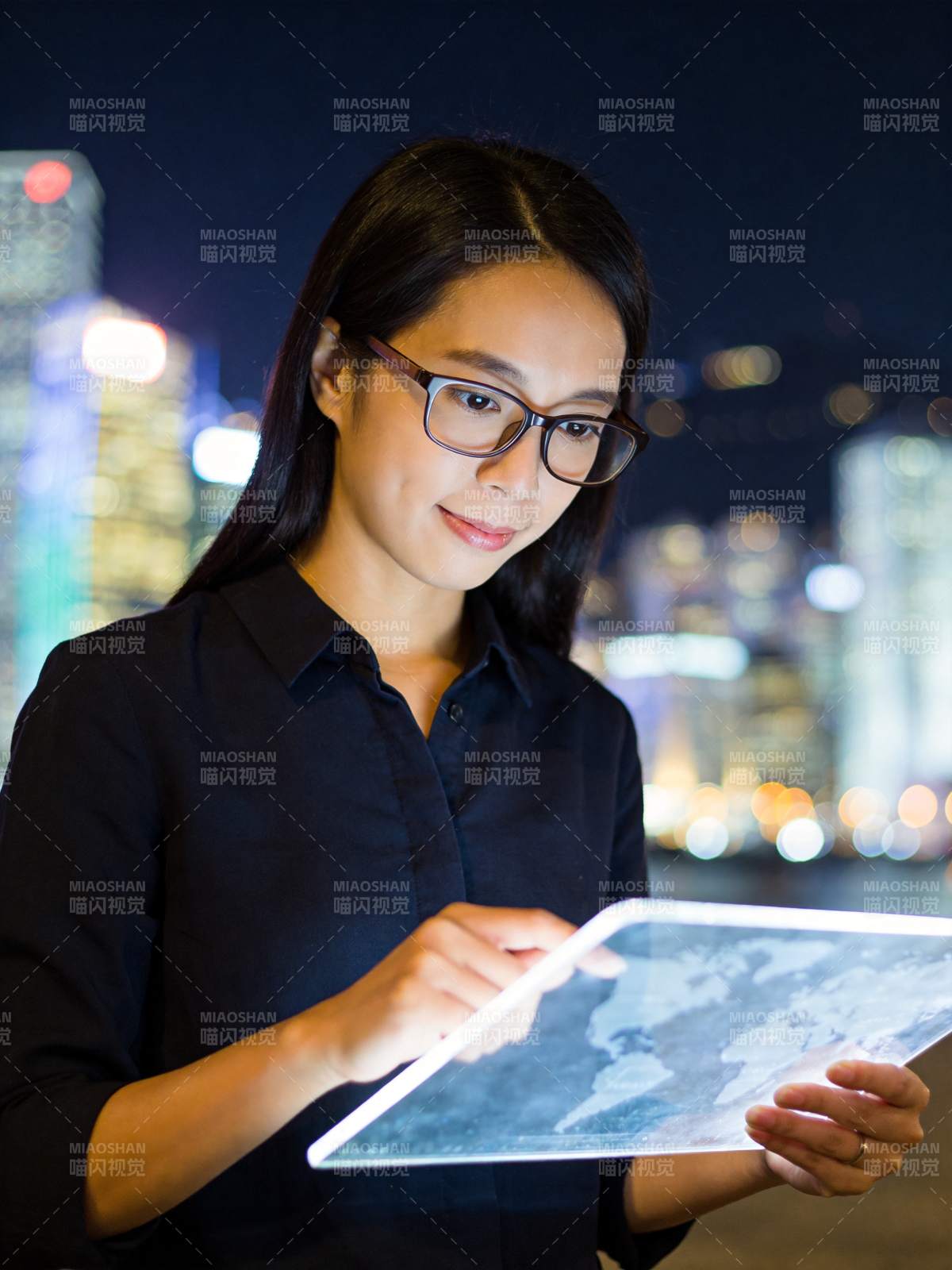 戴眼镜女性夜间手持平板查看世界地图图片