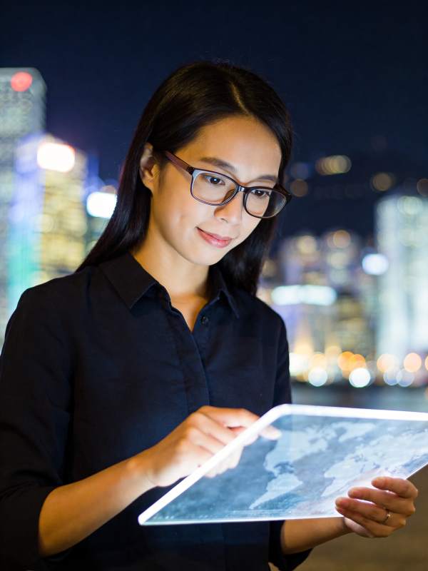 戴眼镜女性夜间手持平板查看世界地图图片