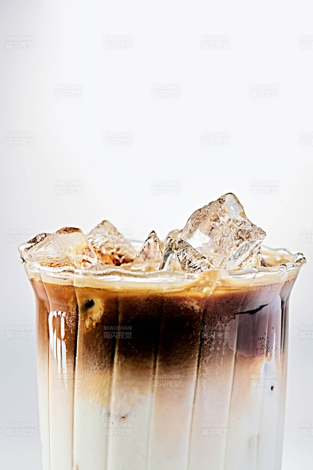 玻璃杯中分层冰镇生椰拿铁咖啡特写图片