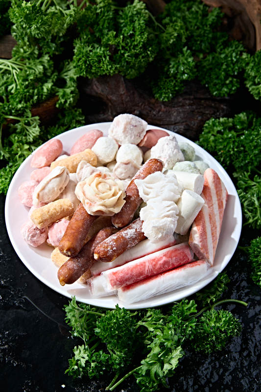 白圆盘盛装多种类混合冷冻火锅食材图片
