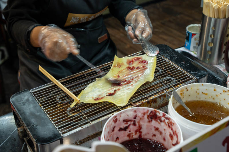 烤乳扇摊主刷酱制作中图片