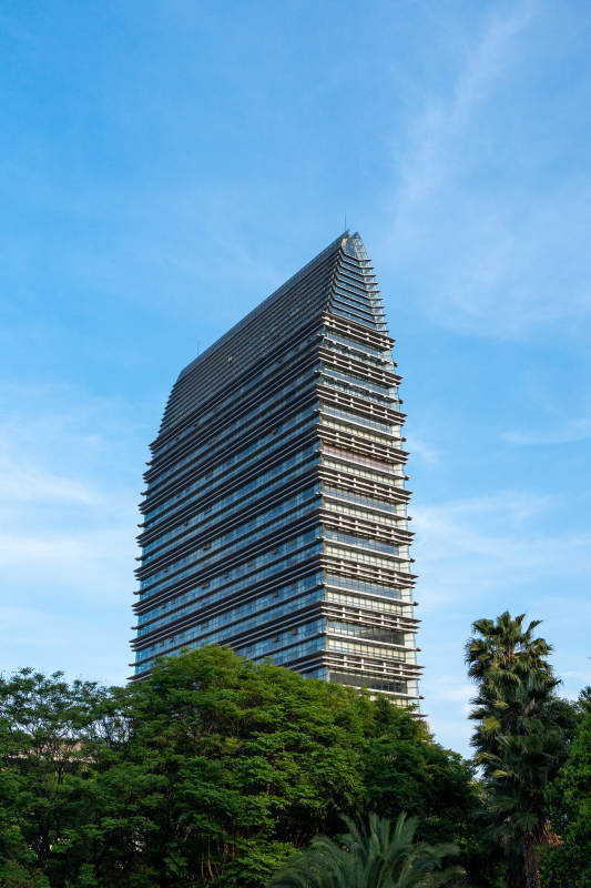 云南昆明现代高楼耸立蓝天绿树间图片